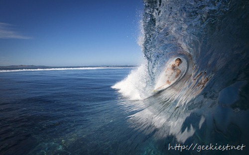 Female surfer in the tube of a breaking wave, Fiji